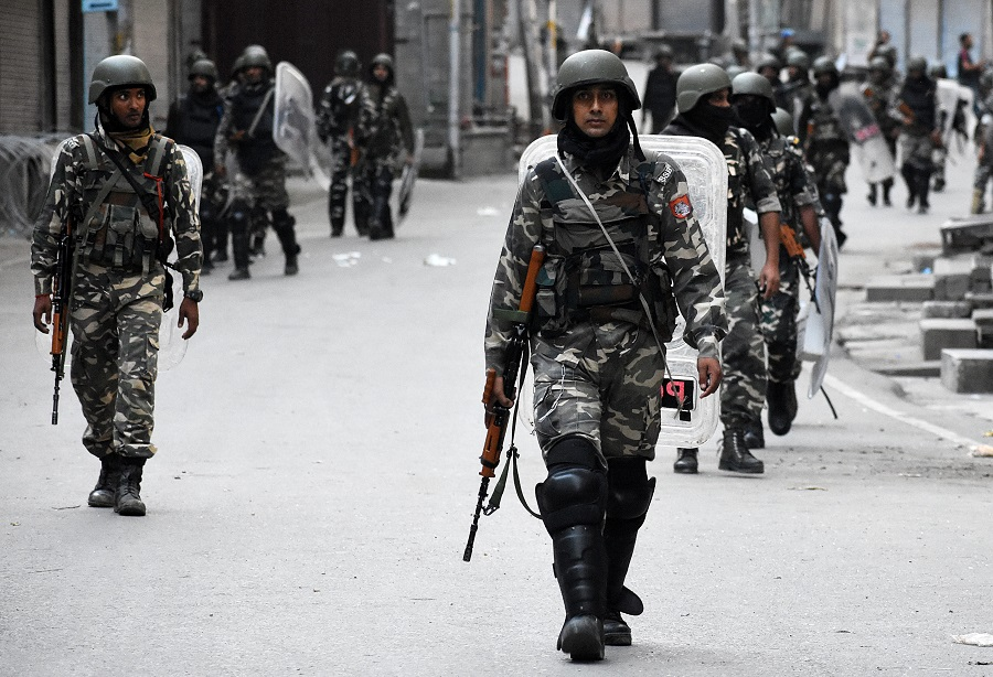 Security forces in camouflage patrolling an urban area in Kashmir, indicative of preventive detention enforcement 