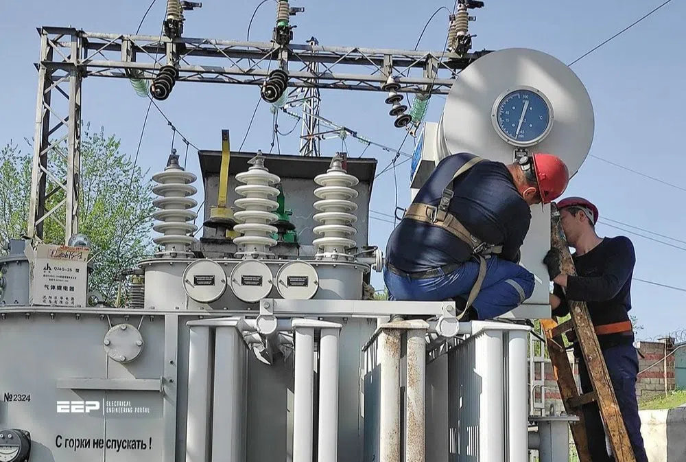 Workers performing electrical transformer installation and maintenance at an outdoor substation
